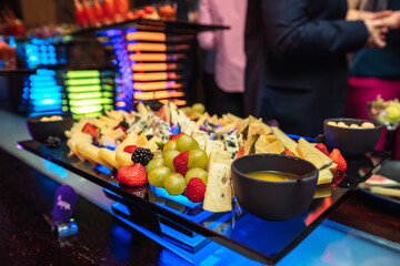 A plate of cheese and fruits at the party in bar