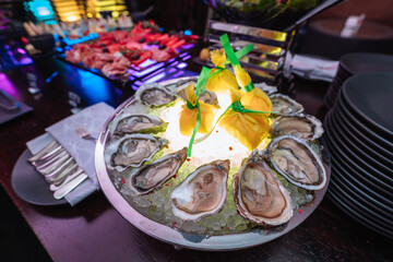 Fresh oysters with lime on a round plate. Oyster season. Macro-seafood dish. Oyster on the half shell