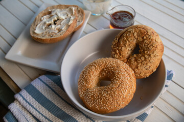 Three types of bagels with cream cheese and honey ona white wood table - obrazy, fototapety, plakaty