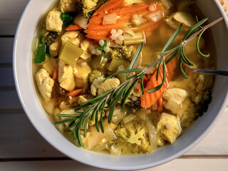 Top View of Chicken Couscous Soup with Fresh Bread on white wood table