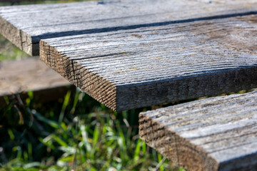 Fototapeta premium Part of a wooden table with weathered old planks in the park on a sunny spring day. Close up and copy space for text or design