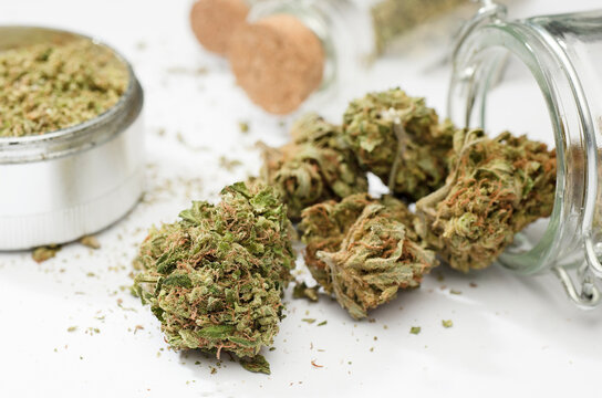 Close up of medical marijuana buds , crusher , glass bottles, white background