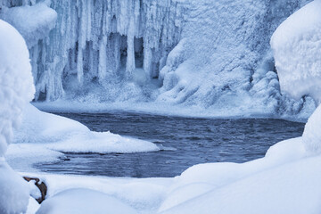 Stones with snow caps and ice in the water of frozen river in winter.