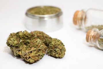 Close up of medical marijuana buds , crusher , glass bottles, white background