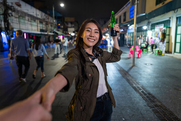 Portrait of Asian woman traveler hold boyfriend's hand, walk on street.