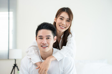 Portrait of Asian new marriage couple sit on bed and looking at camera.