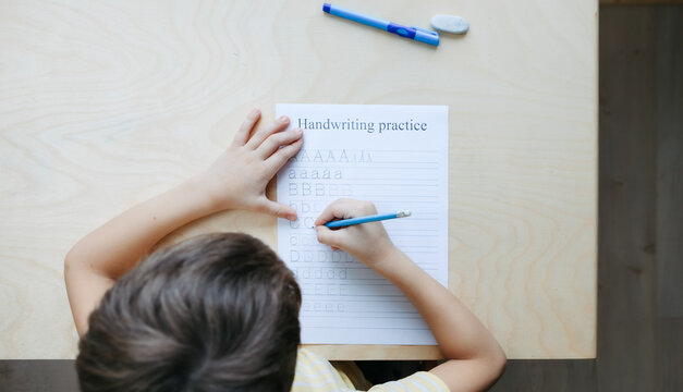 A schoolboy doing math lesson sitting at desk in the children room
