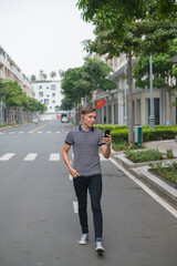Fototapeta na wymiar Young caucasian guy walks down the street and makes video call by the phone
