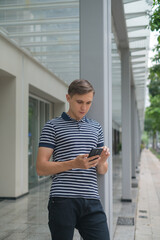 Fototapeta premium Portrait of Young caucasian guy in casual clothing looking at his phone