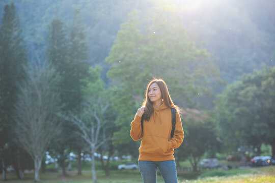 Portrait image of a female traveler with backpack looking at a beautiful nature view while traveling in the park