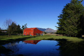 Abandoned red house in rural scenic mountainous landscape of New Zealand