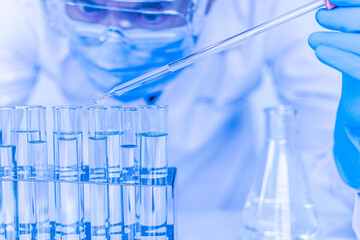 A male scientist wearing protective goggles and wearing gloves is dripping chemicals to test vaccine monkeypox virus. Biochemists are conducting experiments to discover new drugs. Work in science labs