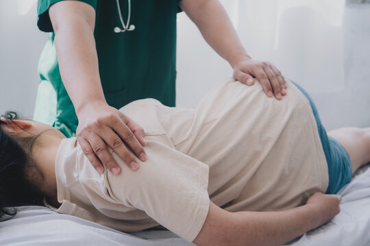 Concept of physical rehabilitation. A doctor or physiotherapist helps to heal a young woman's back. and give advice within the rehabilitation center.