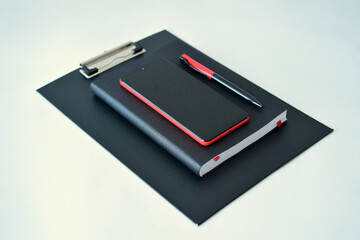 Office supplies. A black diary and a red and black pen, a smartphone. Close-up of the set.