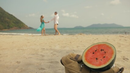 The cheerful love couple in blur, against the background of a watermelon on tropical sand beach sea. Romantic lovers two people caucasian spend summer weekend in outdoor. White shirt beachwear.
