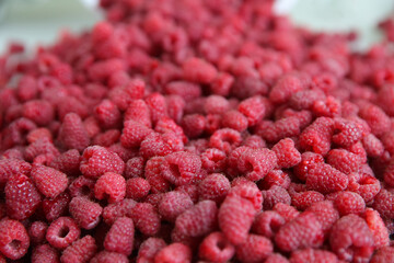 lot of fresh sweet raspberries scattered from a bucket on a white background