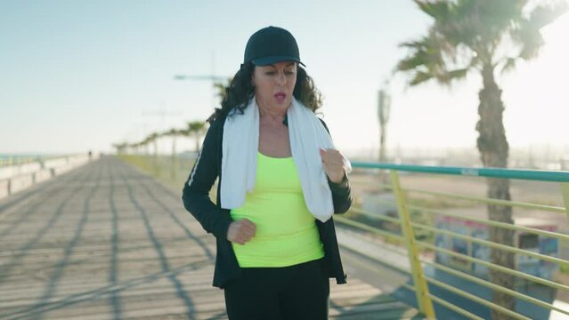 Middle age woman wearing sportswear running and looking stopwatch at street