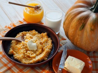 Millet porridge with the addition of pumpkin on a wooden white table with pumpkin fruit. Diet food.