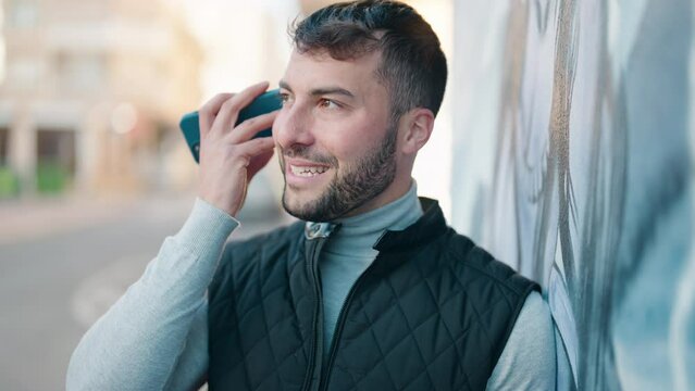 Young hispanic man smiling confident listening audio message by the smartphone at street