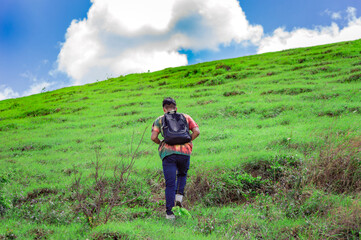 Fototapeta na wymiar Young man climbing a hill with blue sky , back traveler climbing a hill, back guy hiking