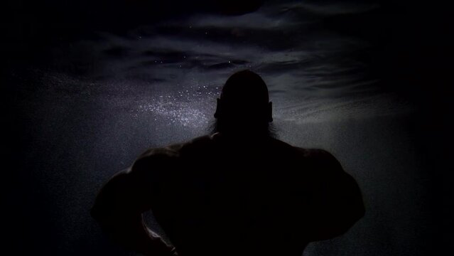 underwater shot with muscular man, silhouette of brawny man, rear view, powerful and strong jock