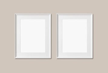 Picture frame mockup. Set of two vertical white frames on warm neutral wall background. Empty,...