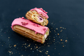 Close-up of a cut berry eclair on a black background.
