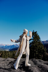 young woman in autumn clothes stands on a rock blue sky lifestyle