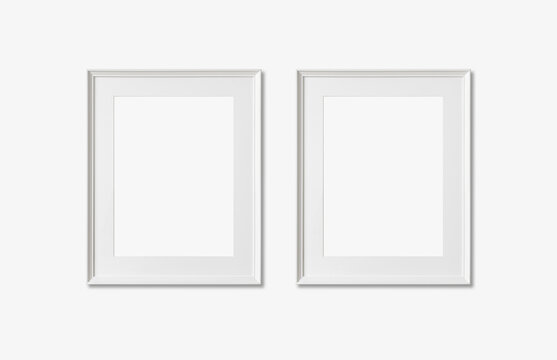 Picture frame mockup. Set of two vertical white frames on white wall background. Empty, blank template for artwork, painting or poster.