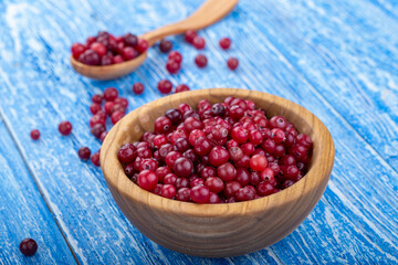 Fresh cranberries in a bowl on a wooden table.