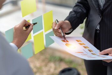 Businesspeople pointing and explaining graphs, charts and analyzing plans with colleagues in company meeting.