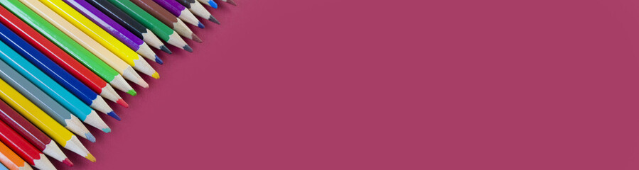 Fototapeta premium colored pencils on a red background close-up. drawing tool. Banner for insertion into site.