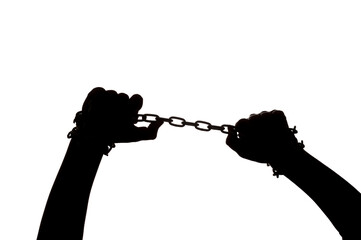 Dark silhouette of hands in handcuffs trying to break the chain on a light background - obrazy, fototapety, plakaty