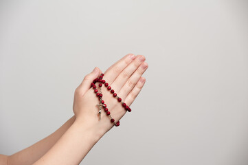 folded hands of a young man holding a rosary during of a pray