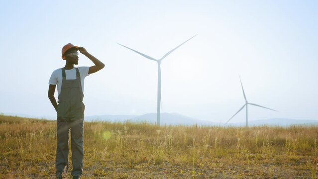 Engineer standing on field with windmills. Dreaming of a clean and sustainable future for generations to come, heartwarming uplifting picture of clean energy for the environment.