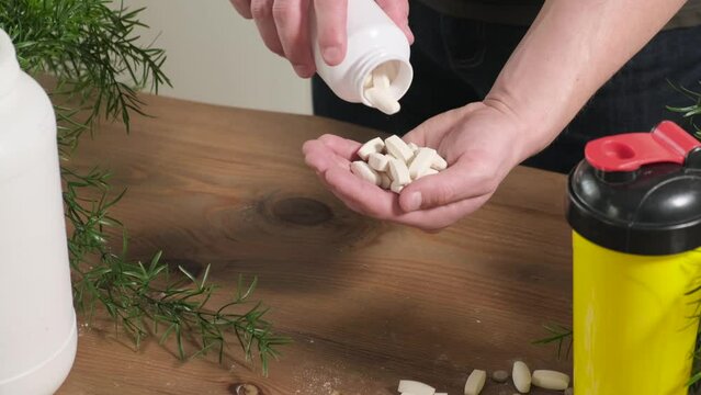 The athlete pours amino acids in tablets into the palm of his hand