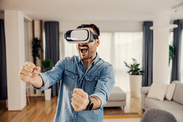 A modern man playing VR game with VR headset on his head, driving a car at his cozy home.