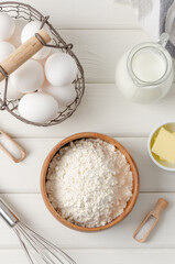 Ingredients for making traditional thin pancakes or crepes on a white wooden background. Recipe step by step. Food for Maslenitsa.
