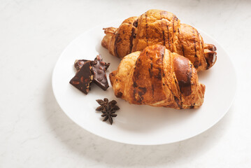 delicious, tasty, crispy croissants, chocolate on plate on light marble table