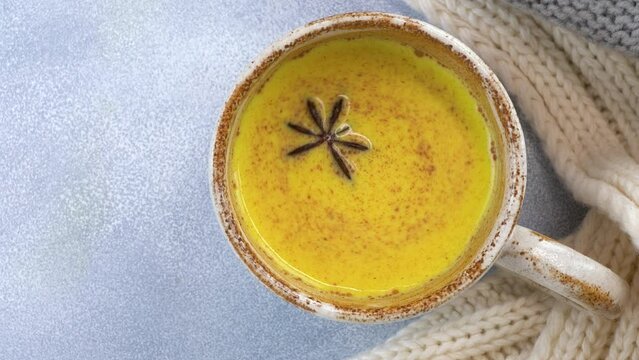 Star anise is spinning in a glass of turmeric golden moon milk. Healthy drink.
