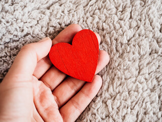 Man's hand holds a card in the shape of a heart. Close-up, indoors, view from above. Day light