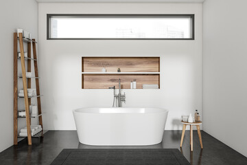 Bright bathroom interior with bathtub, shelf with towels, stool, window