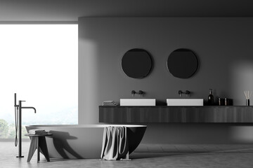 Dark bathroom interior with bathtub, sink and mirror near window