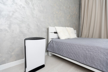 Air purifier in cozy white bedroom for filter and cleaning removing dust PM2.5 HEPA and virus in...