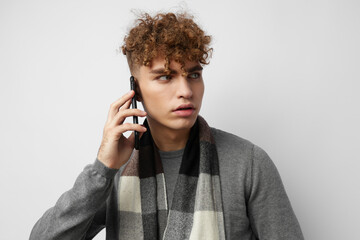 handsome young man in a plaid scarf looking at the phone fashion light background