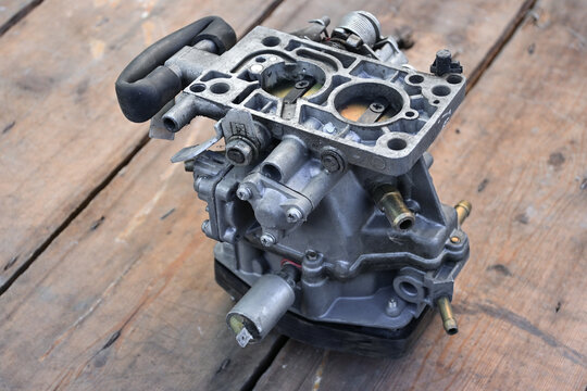 Close-up of a gasoline carburetor. Car repair in the workshop. carburetor isolated. removed from the engine. wooden background.