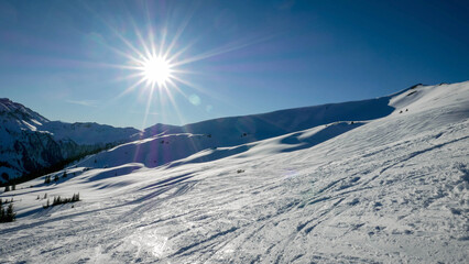Sun over a snowy alpine ski slope  - 488317717