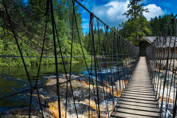 Suspension bridge and wooden house on Ruskeala waterfalls in Karelia, Russia