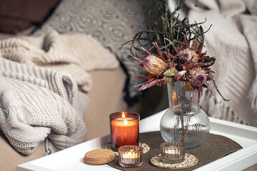 Home composition with a bouquet of protea flowers and candles.