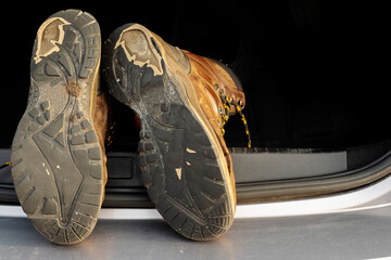 Pair of old brown hiking shoes on a car boot. Reliable leather worn out boots. Long walk or travel...